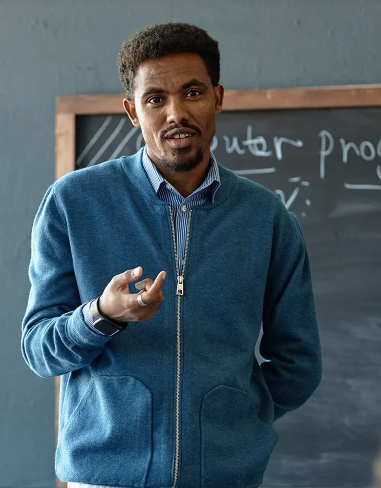 Male teacher standing in front of a classroom blackboard